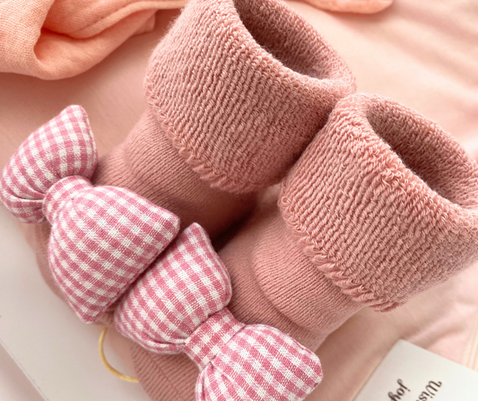 Pink textured scrunchies with a checkered bow on a soft pink background